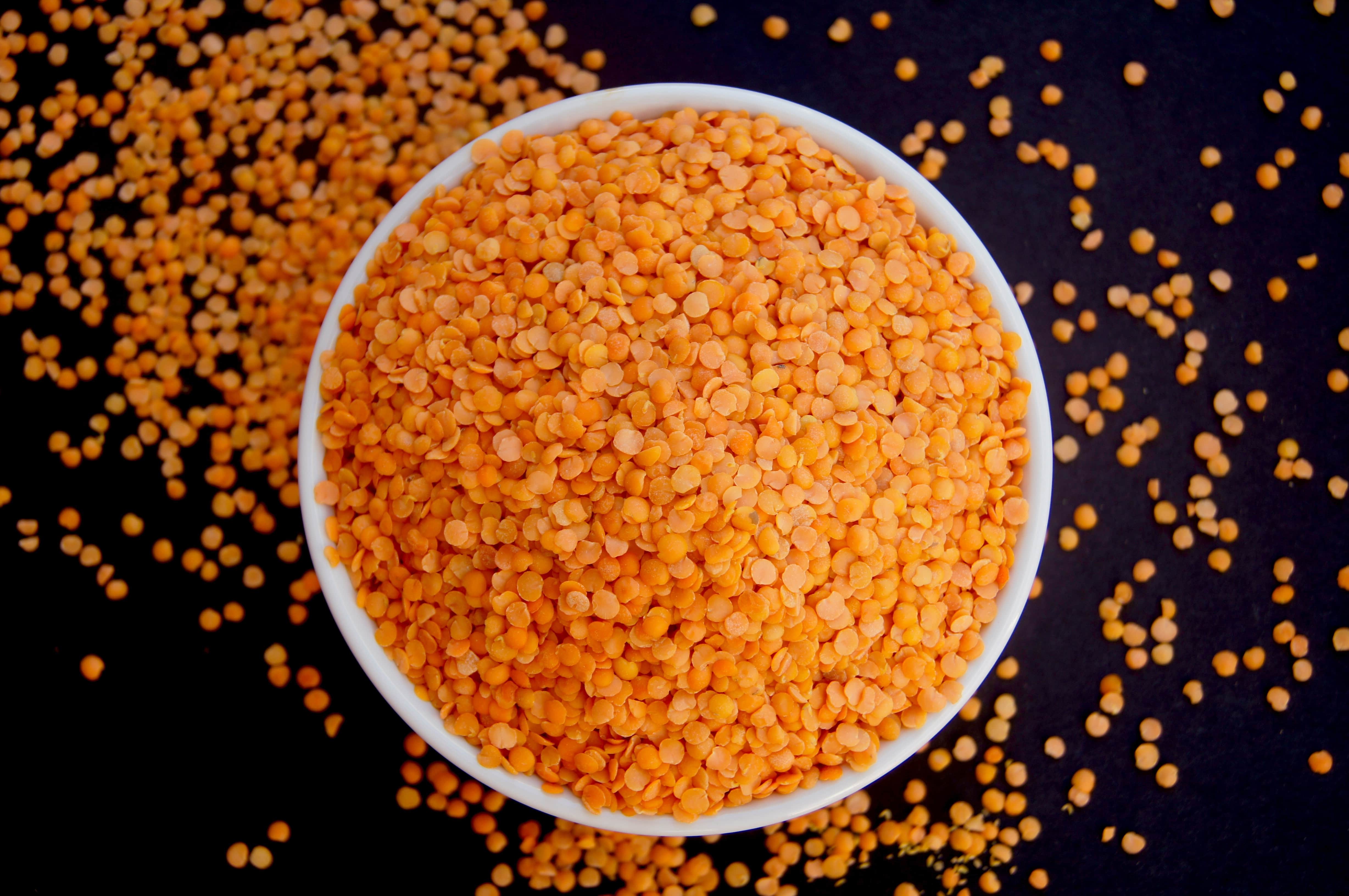 Raw Masoor Dal (red lentils) spilling over in a bowl