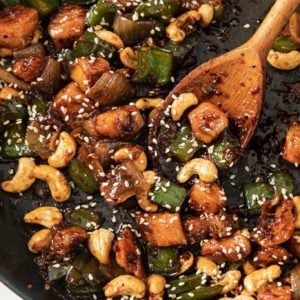 Spicy Cashew Chicken in a skillet with a wooden spoon