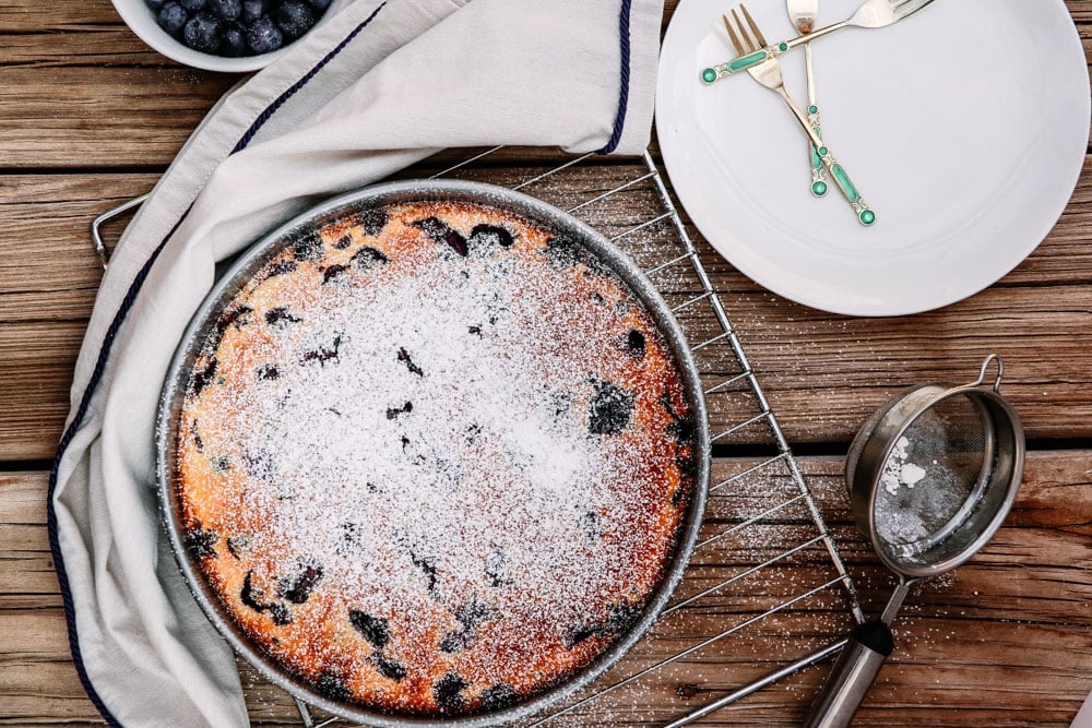 Gluten-Free Blueberry Lemon Clafoutis dusted with powdered confectioners sugar in a baking pan.