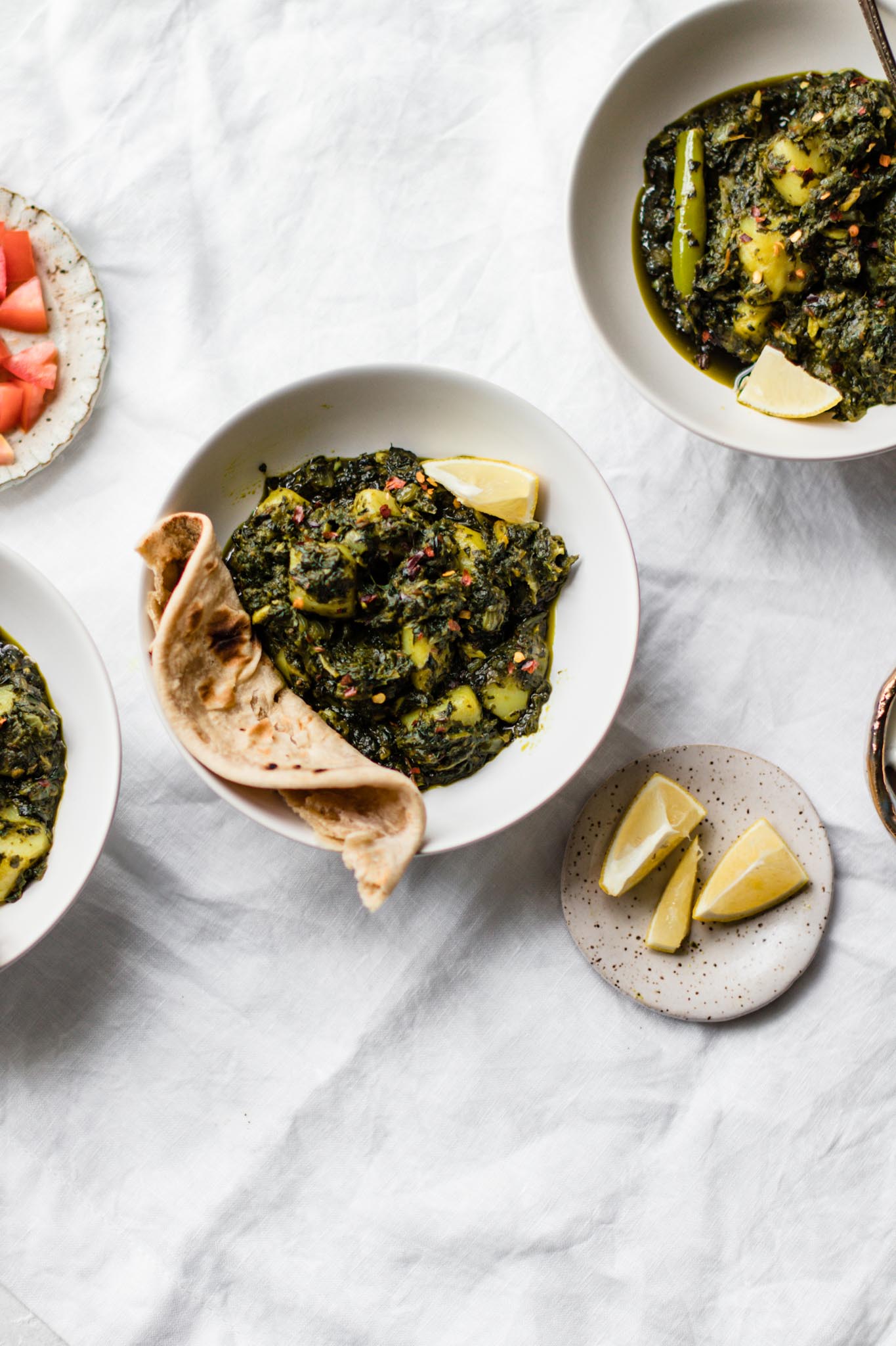 Bowls of Spinach and Potato Curry (Aloo Palak) with lemon on the side