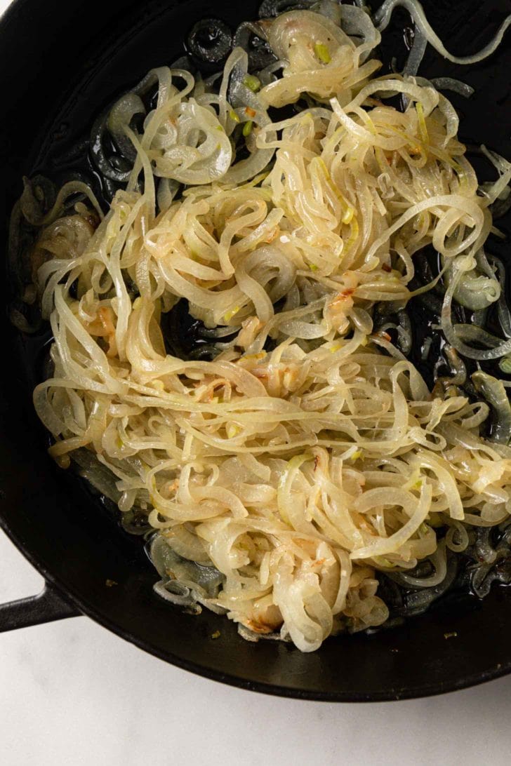 onions being sauteed in a black skillet