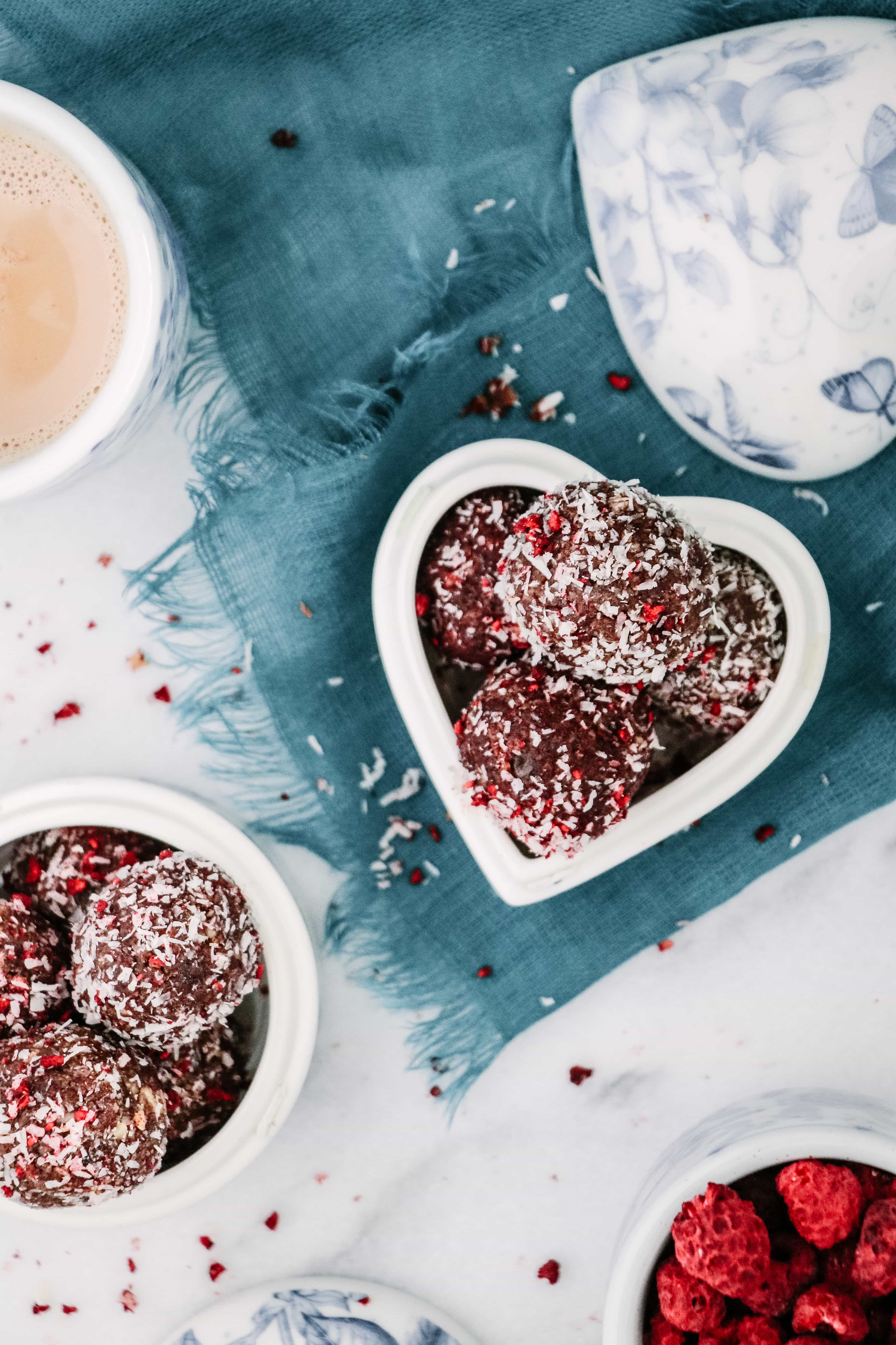 Coconut Raspberry Cacao Bliss Balls in a heart shaped white glass dish.