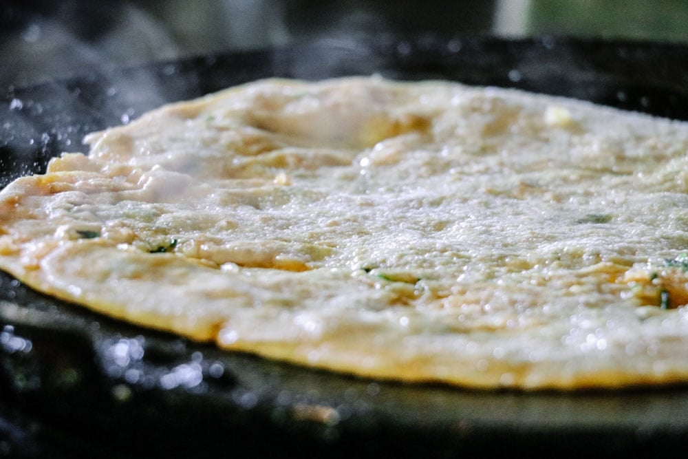 Mooli wala paratha on the griddle being cooked - prepared paratha breakfast recipe