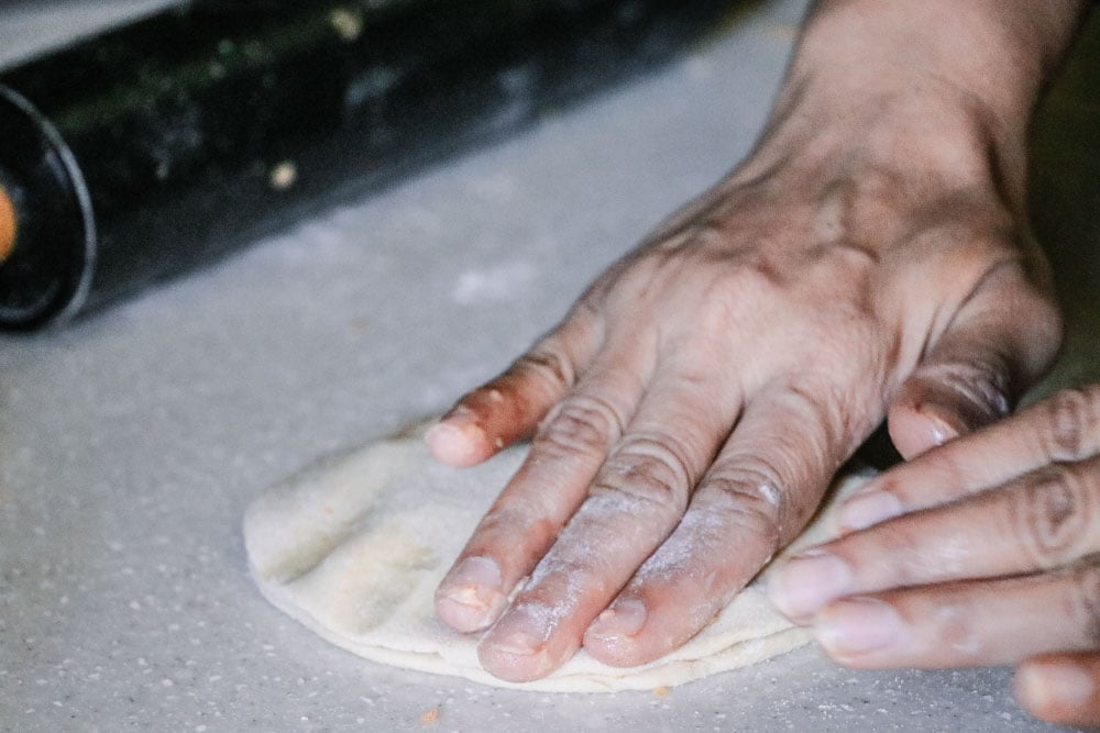 The edges of paratha dough being sealed with hands