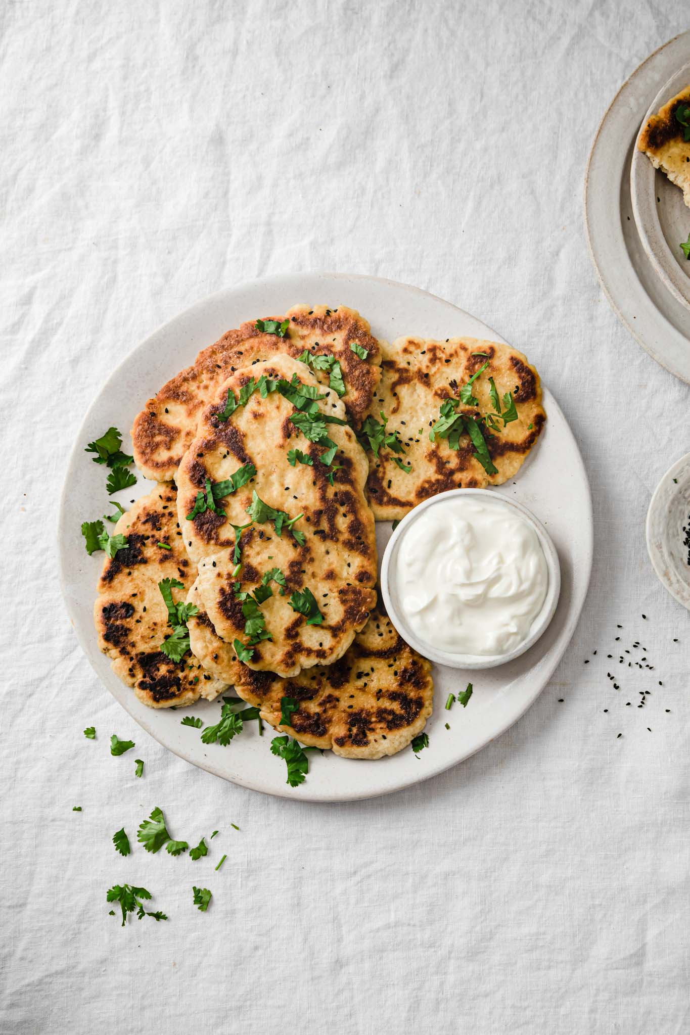 Gluten-Free Naans placed on a white platter garnished with cilantro and served with yogurt 