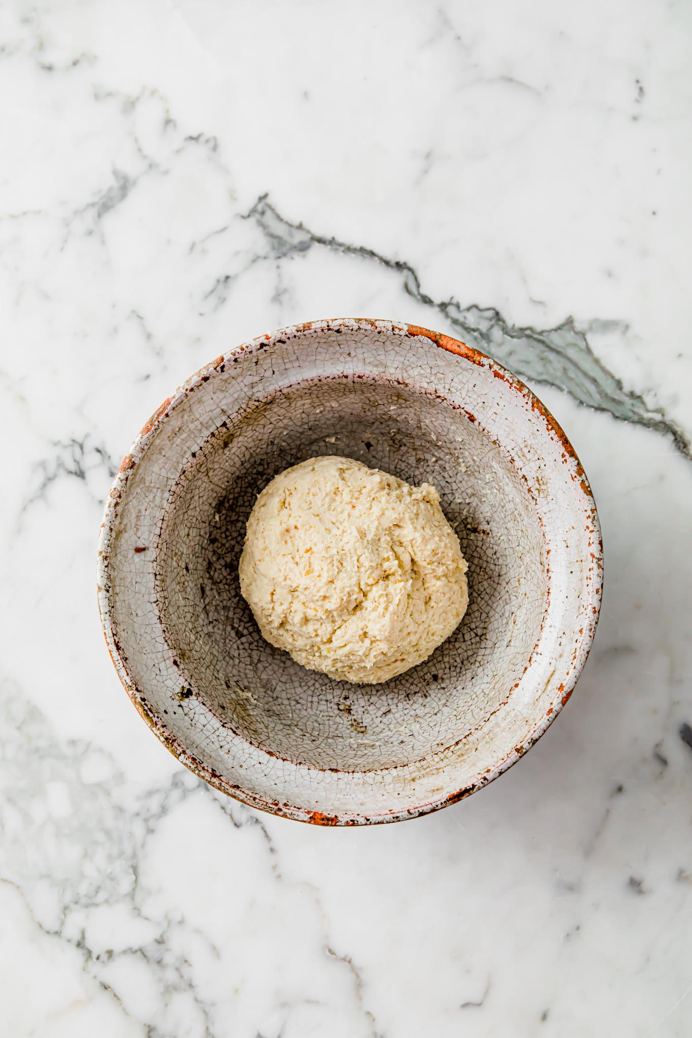 Dough for Gluten-free Naan Bread in a rustic bowl on a marbled surface