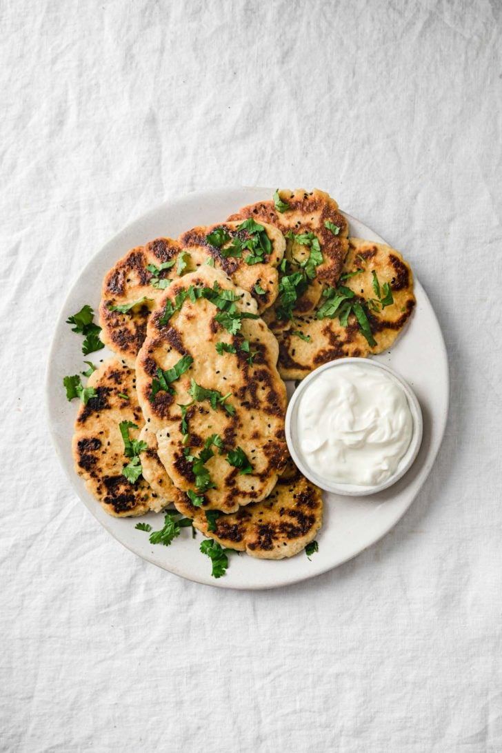 Gluten-Free Naan Bread on a platter with cilantro sprinkled on top and yogurt on the side