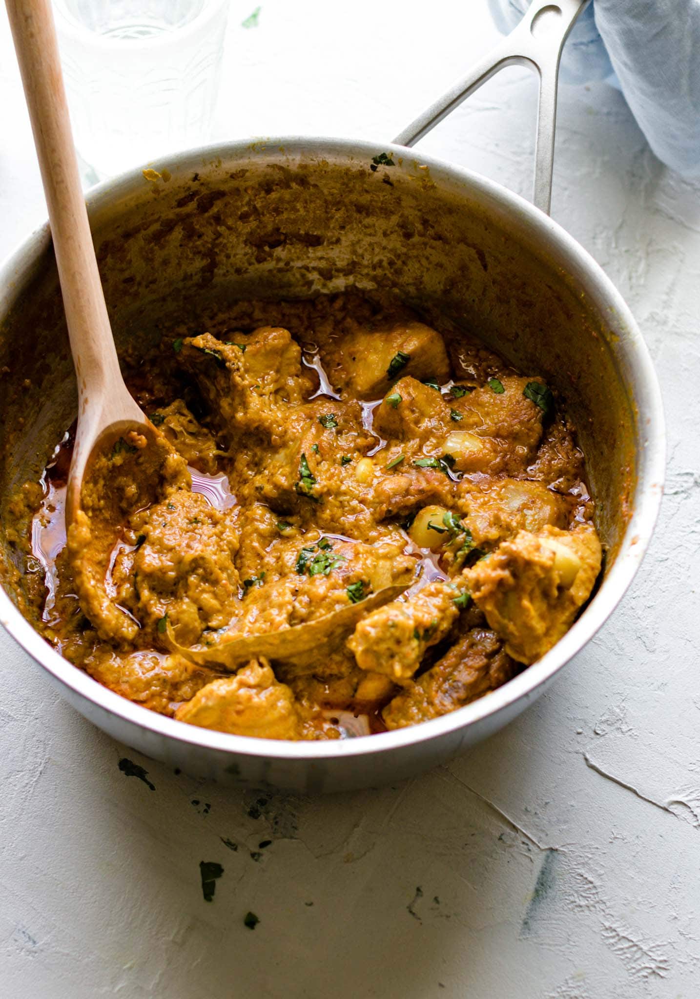 Chicken Korma in a large pot with a wooden spoon
