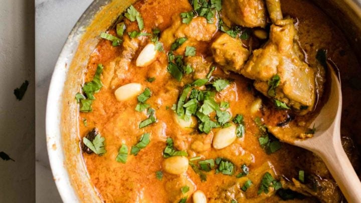 Chicken Korma in a large pot with a wooden spoon.