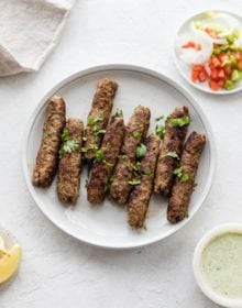 Seekh Kebab garnished with cilantro on a white plate