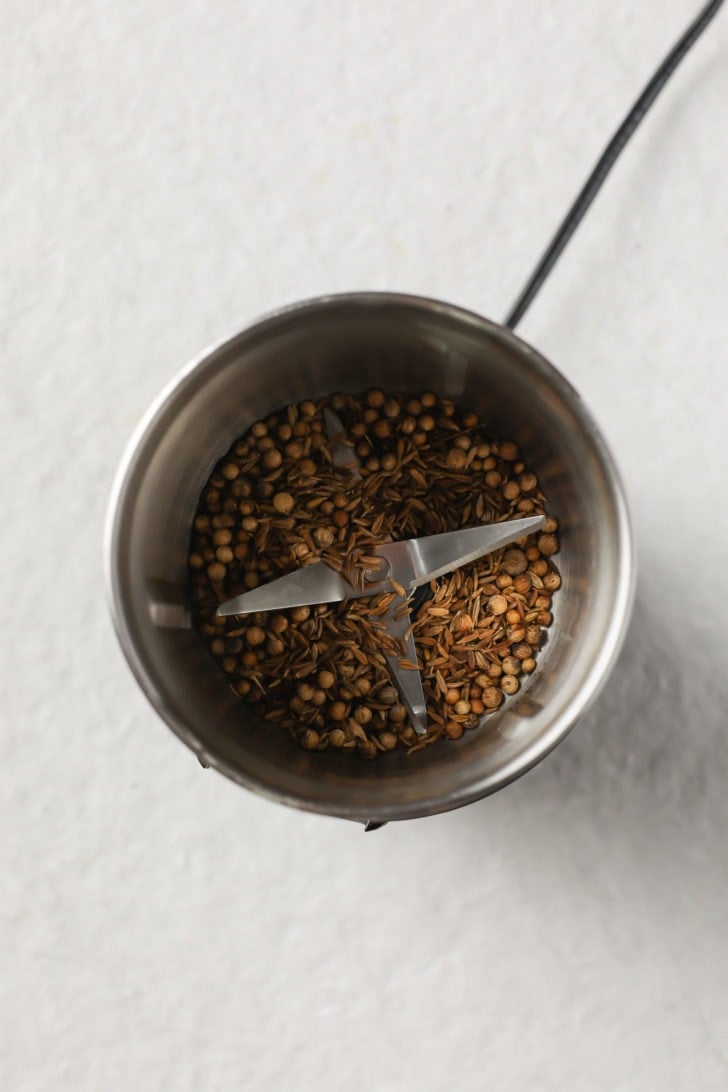 Whole toasted coriander seeds ina spice grinder