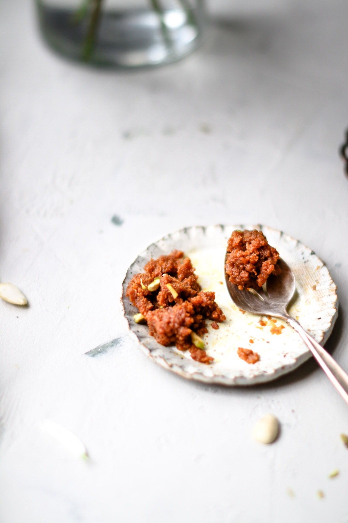 Partially eaten Instant Pot Carrot Halwa on a small clay plate with a silver spoon