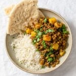 Aloo Keema (Ground Beef and potato curry) in a bowl with basmati rice and naan.