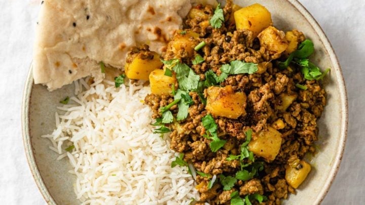 Aloo Keema (Ground Beef and potato curry) in a bowl with basmati rice and naan.