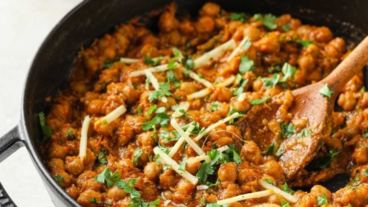 Authentic Chana Masala garnished with cilantro and julienned ginger in a black skillet