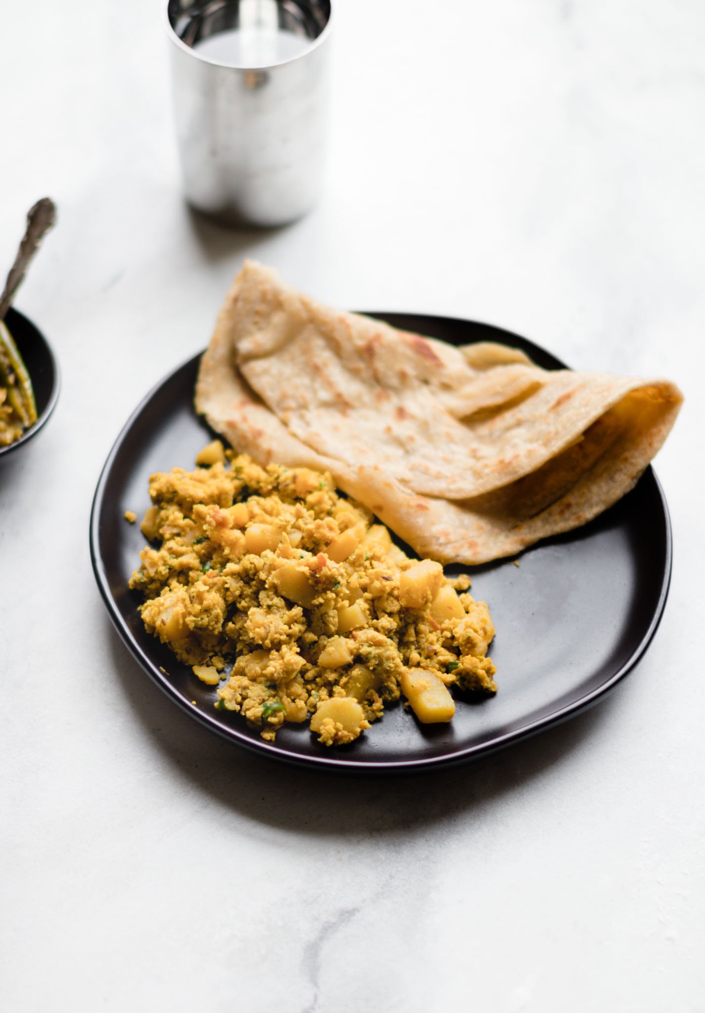 Scrambled Egg and Potato Curry (aloo anday ki bhujia) with Paratha on a black plate