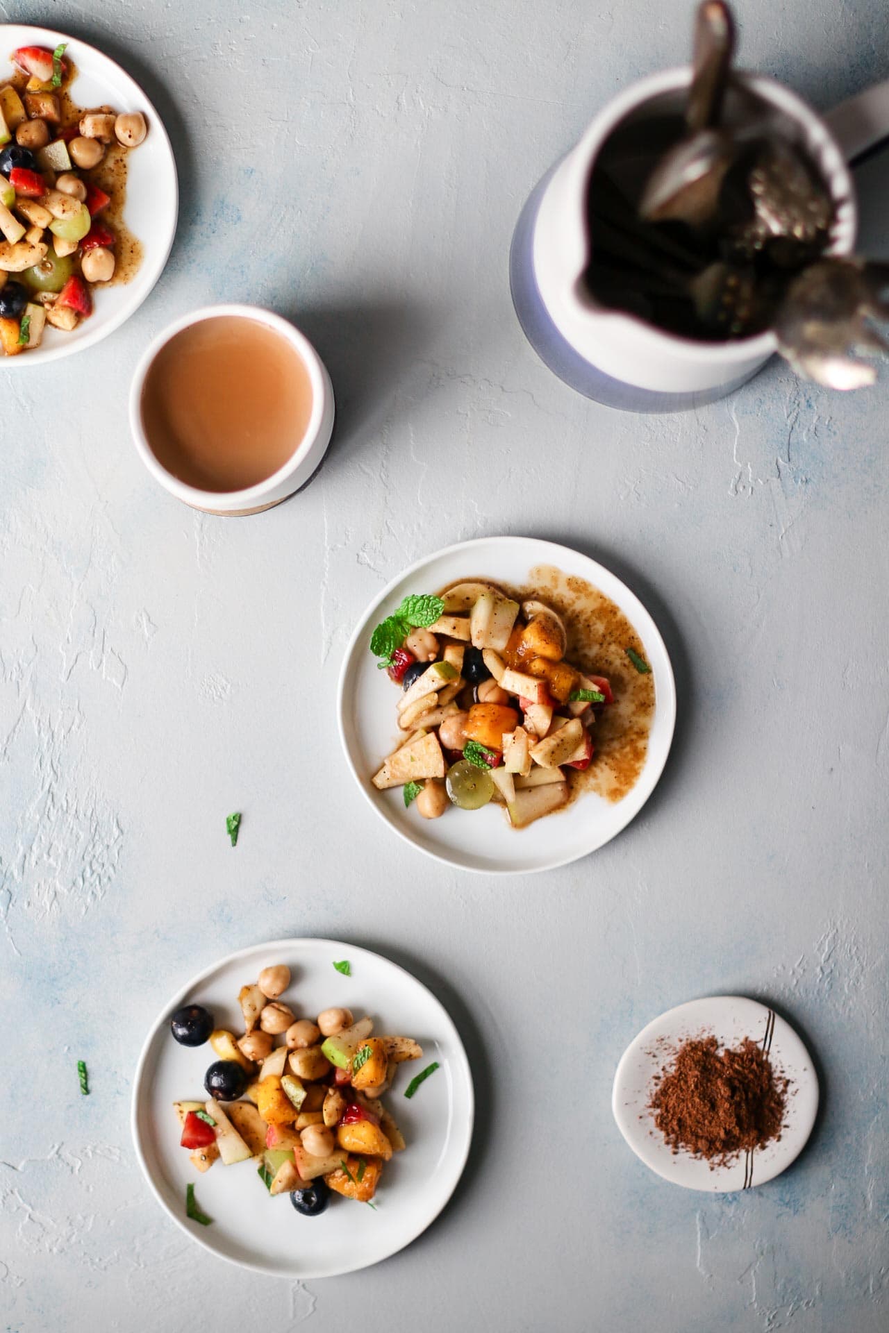 Plates of fruit chaat and a side of chaat masala