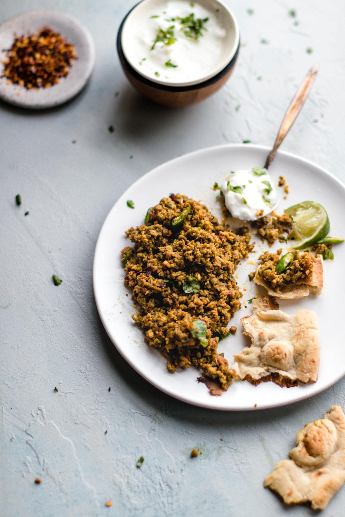 Instant Pot Keema on a white plate with yogurt on a spoon and squeezed lime and pieces of naan bread