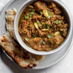 Pakistani Beef Curry (Stew) in a bowl on top of a plate with naan