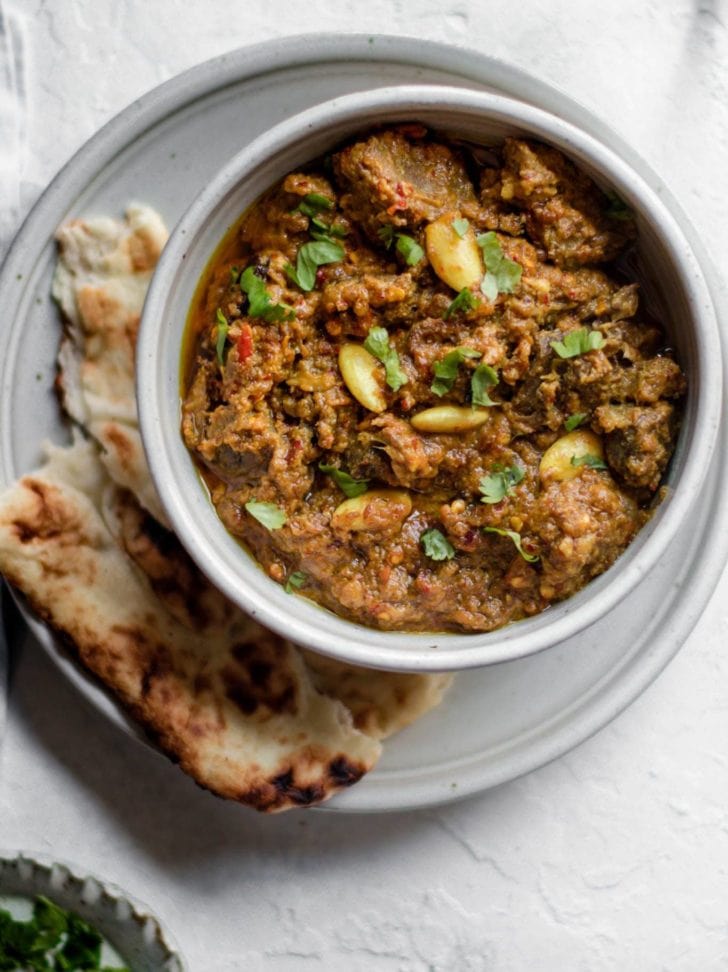 Pakistani Beef Curry (Stew) in a bowl on top of a plate with naan 