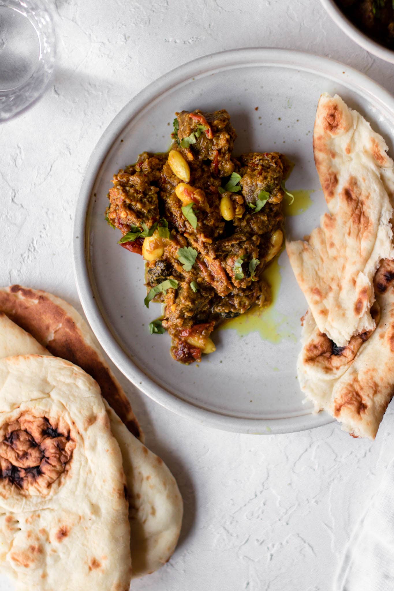 Close up of Pakistani style Beef Curry (Stew) on a plate with naan on the side