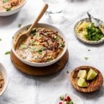 Instant Pot Pakistani-style Haleem made with beef and grains in a white bowl with wooden spoon and garnishing