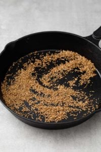 Toasted cumin seeds in a black skillet
