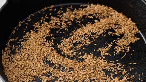 Toasted cumin seeds in a black skillet