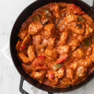 Saucy Chicken Shashlik with bell peppers and onions in a black skillet with a white napkin underneath