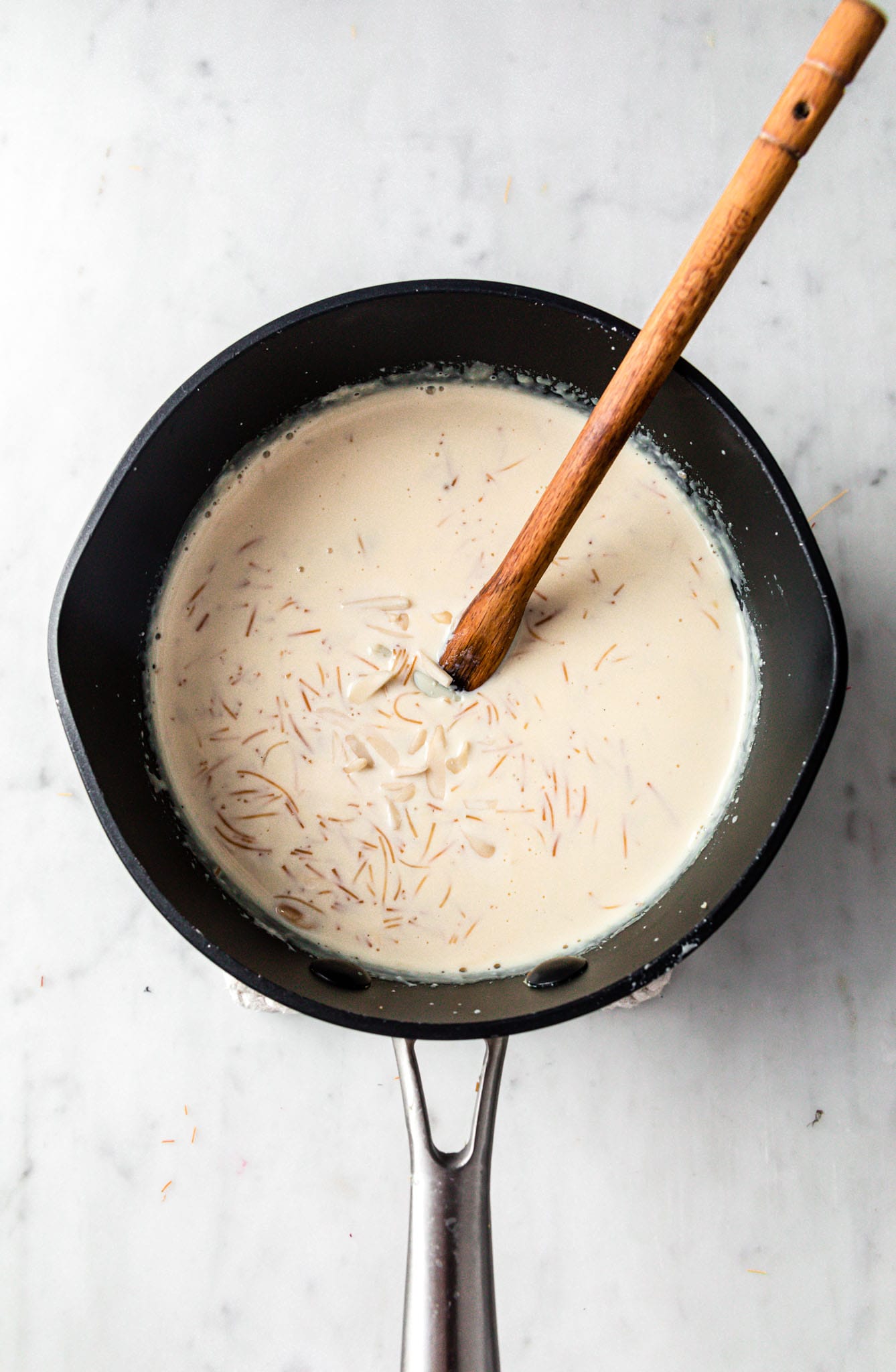 A large saucepan with creamy vermicelli garnished with slivered, blanched almonds