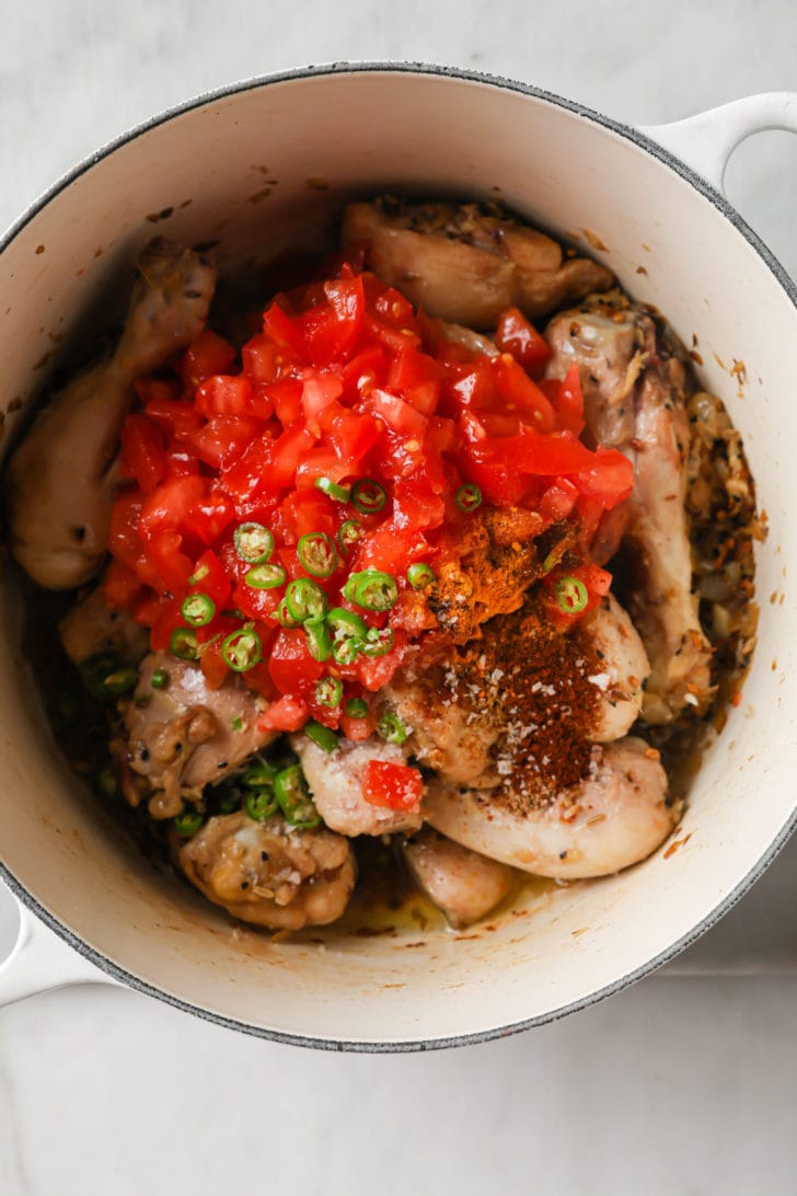 Tomatoes, green chili pepper, and spices added to sauteed chicken