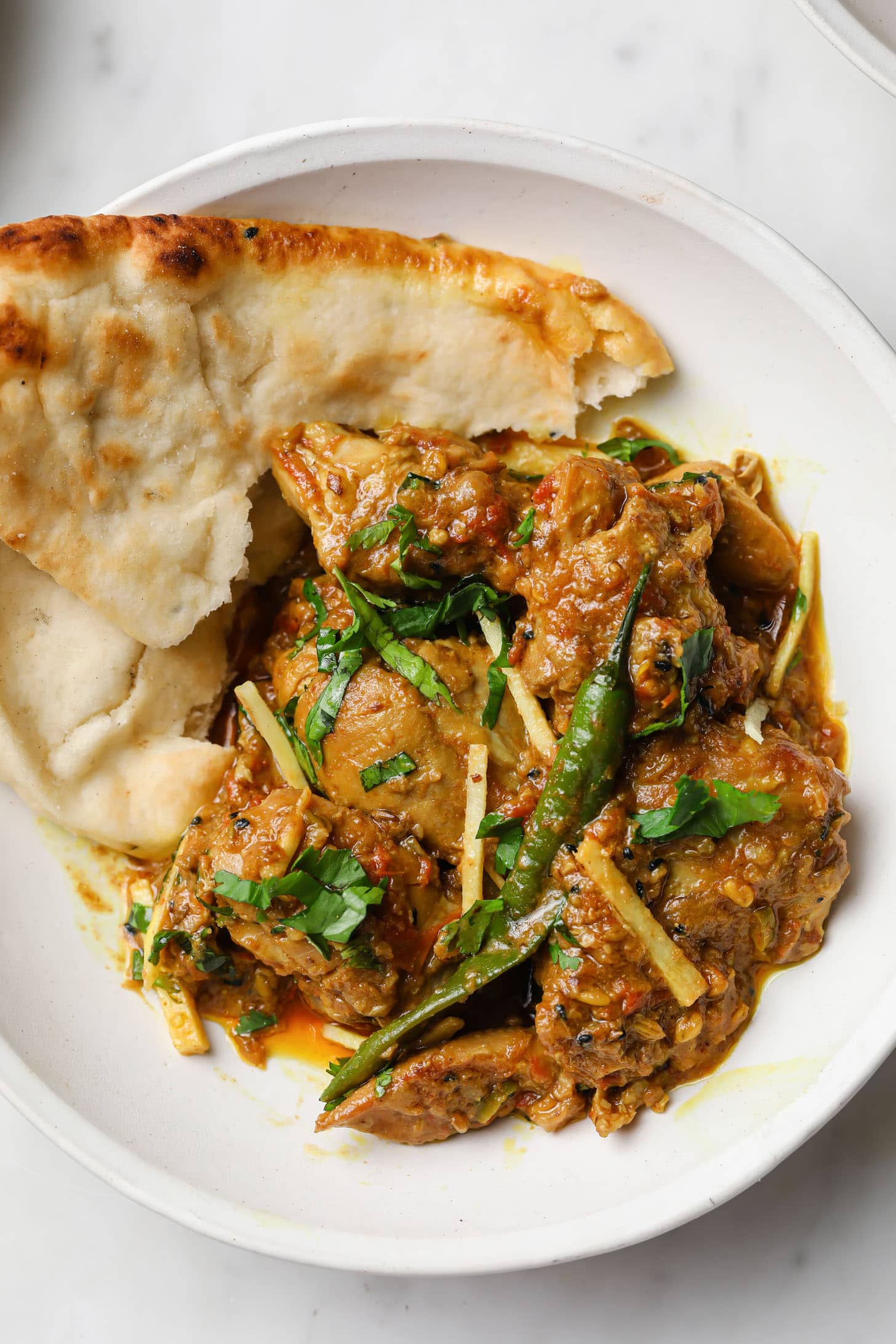 Achari Chicken in a plate with naan on the side