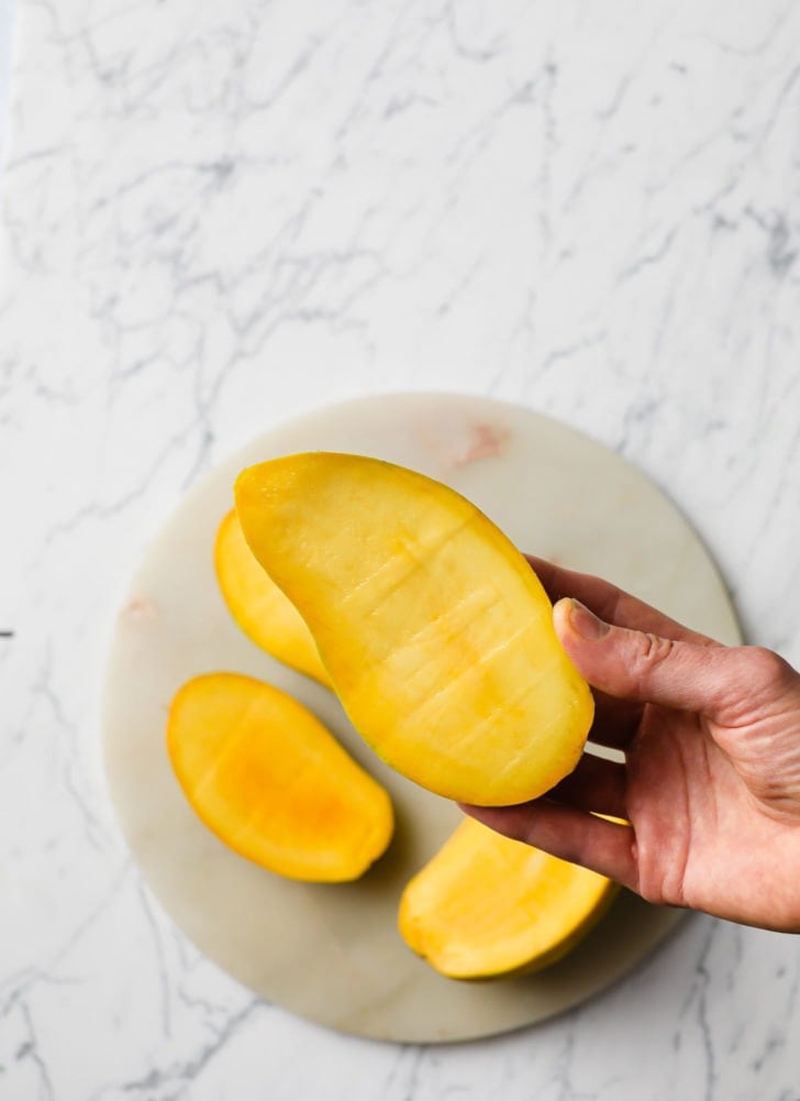 Holding a mango to show texture and color 