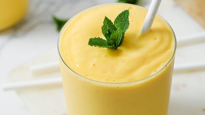 Mango Lassi in a clear glass with white straw