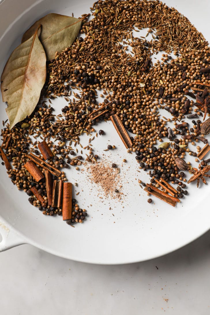 Toasted whole spices in a white pan