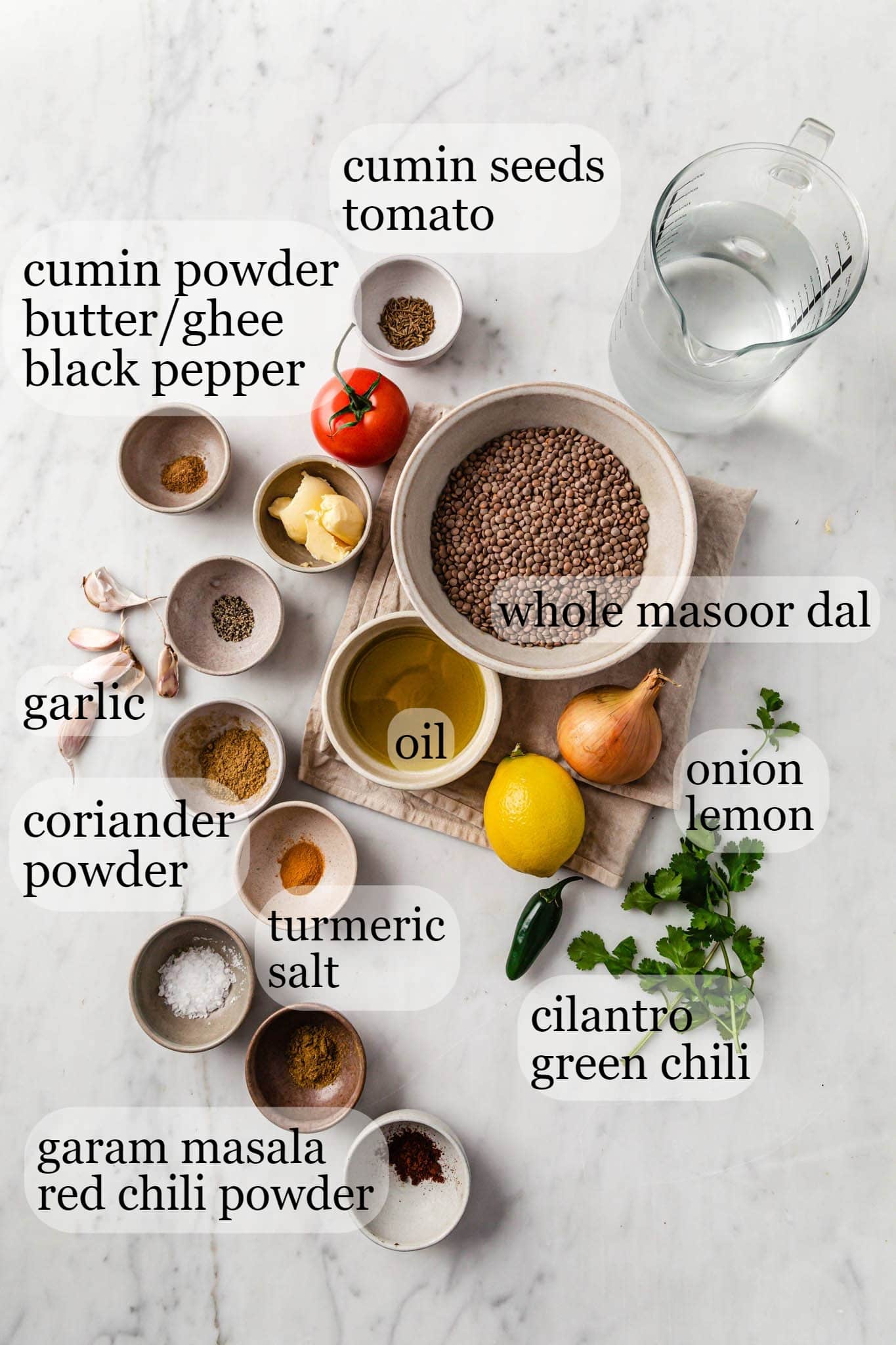 Marble top with ingredients for making Lentil Curry (Whole Masoor Dal)