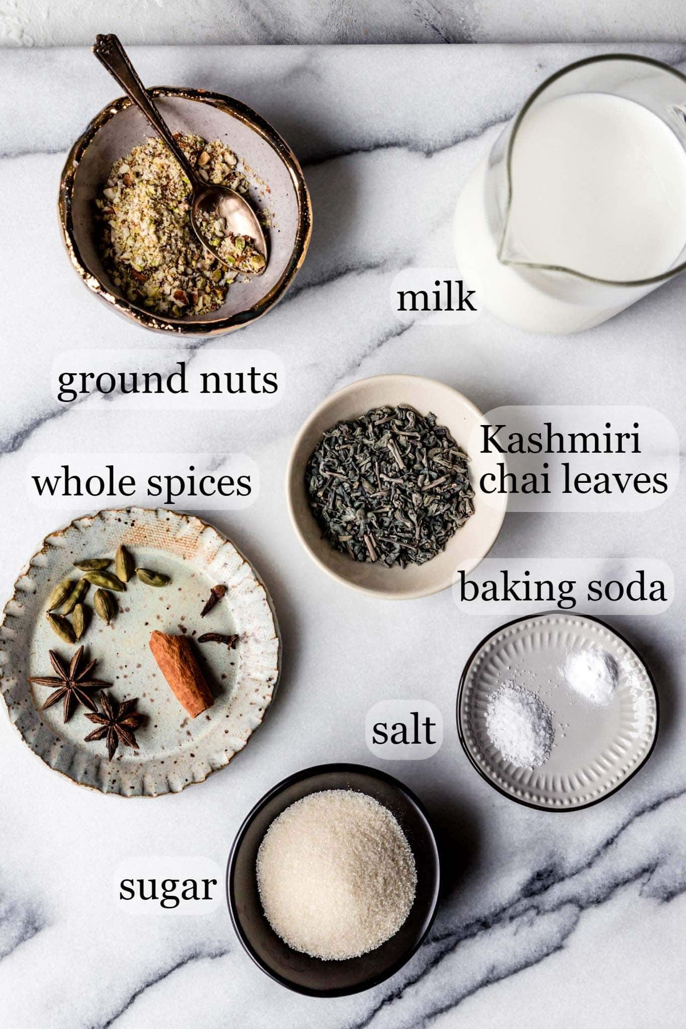 Marble top with milk, half and half, spices, tea leaves, baking soda, salt and sugar for making Kashmiri Chai (pink tea)