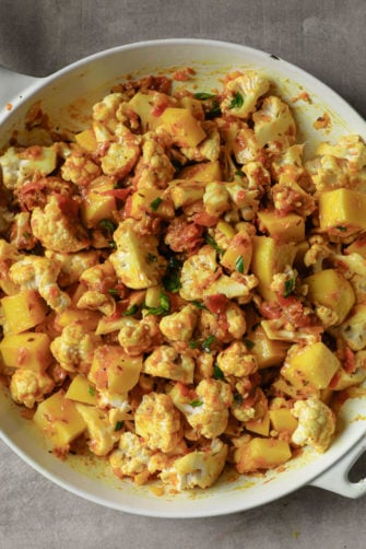 Potatoes and cauliflower ready to be cooked in a white pan