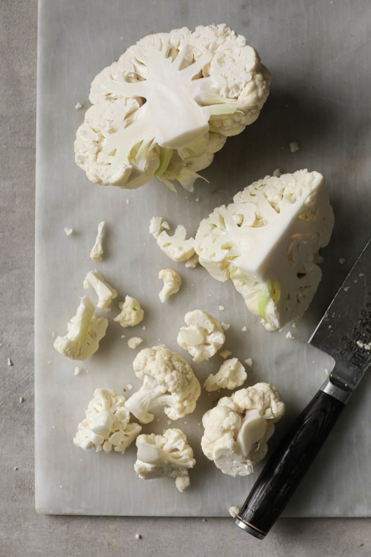 Cauliflower on a cutting board with a knife on the side