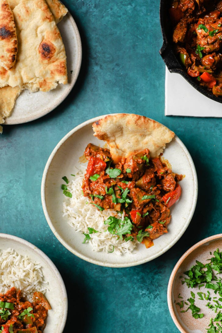 Chicken Jalfrezi in a white bowl with rice and naan on the side