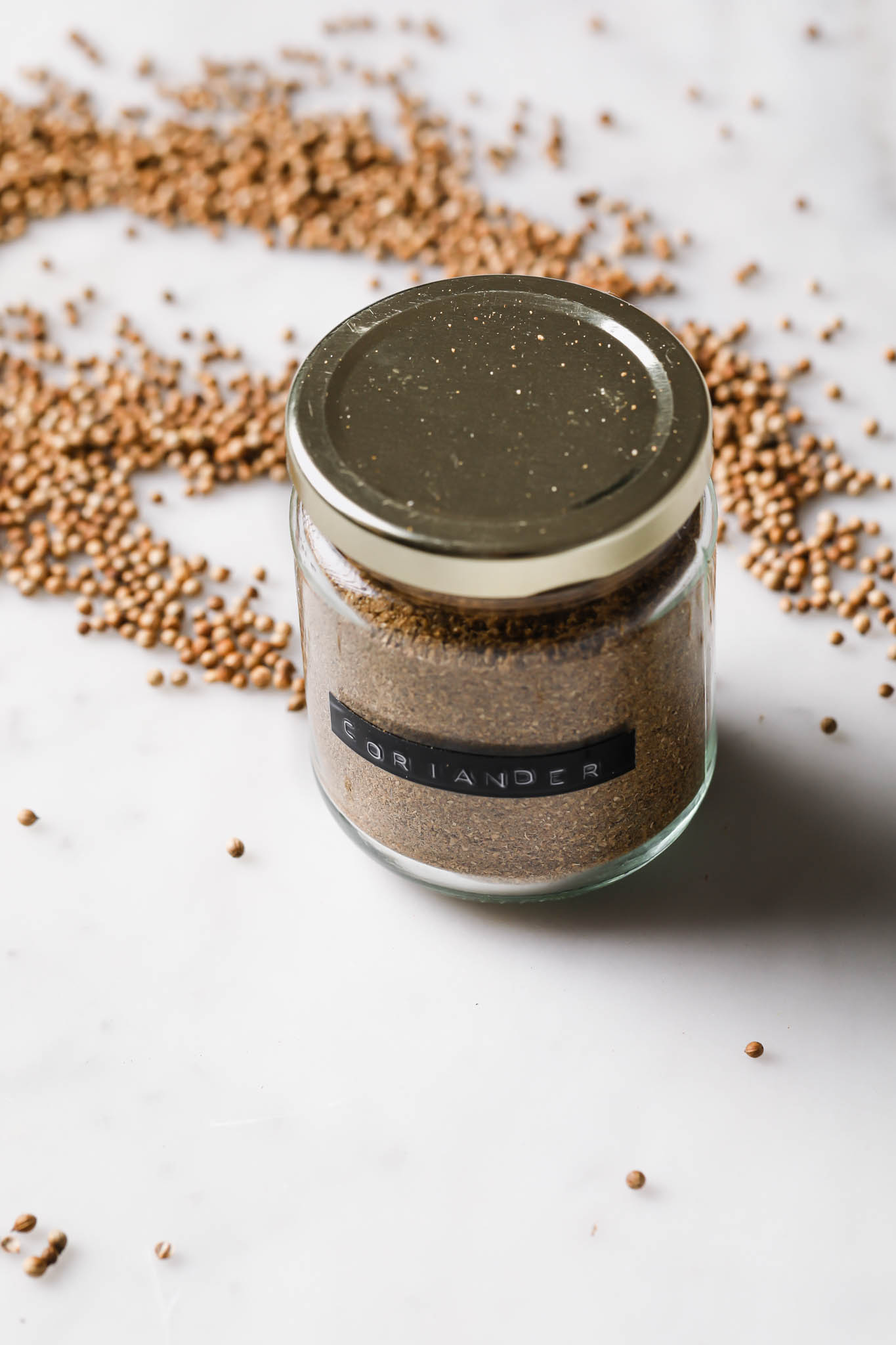 Coriander powder in a small spice jar covered with gold lid.