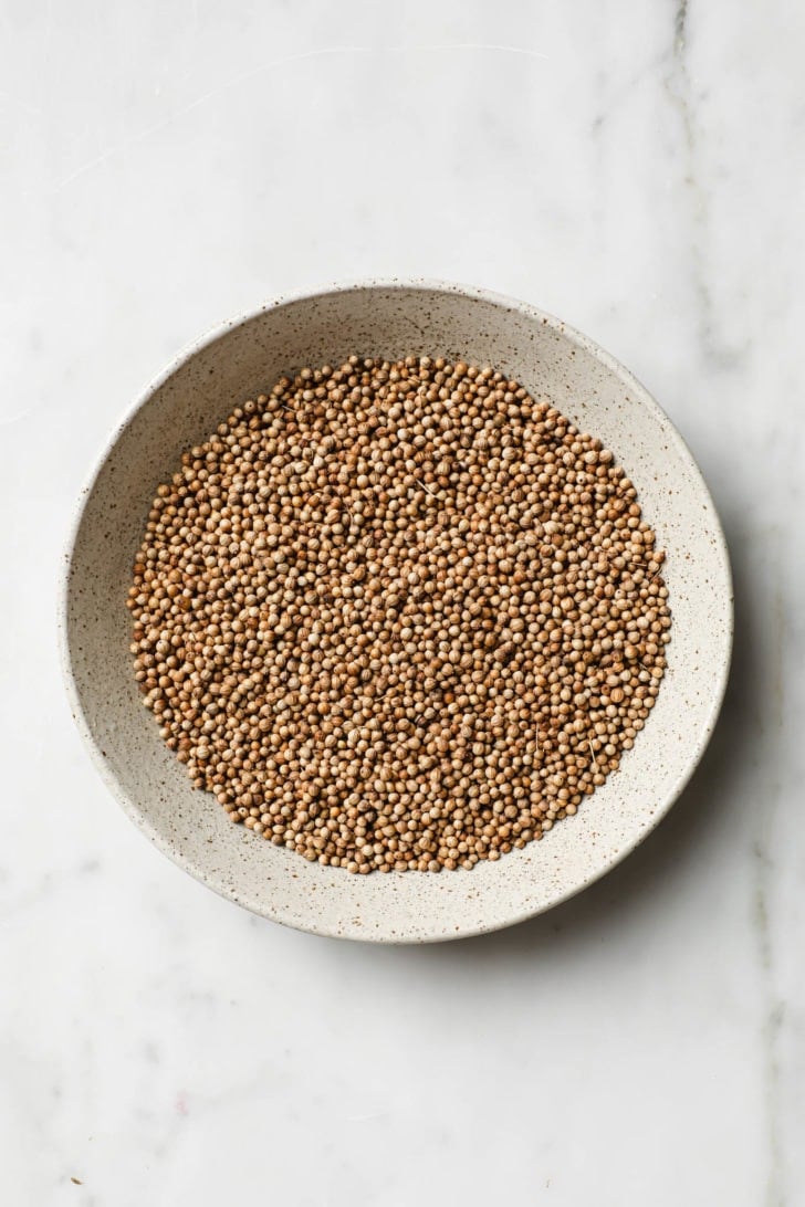 Coriander seeds in a speckled bowl.