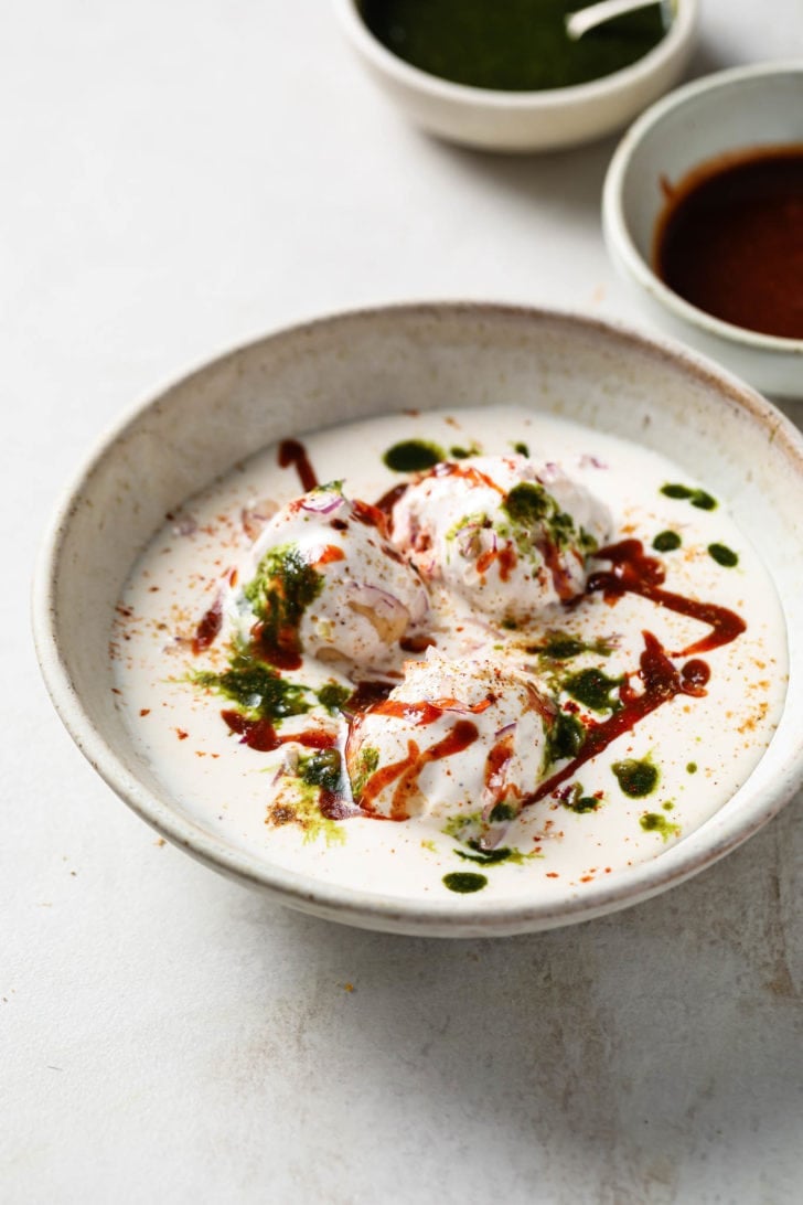 Dahi Bhallas made with dal, doused in yogurt, and topped with chutney and spices.