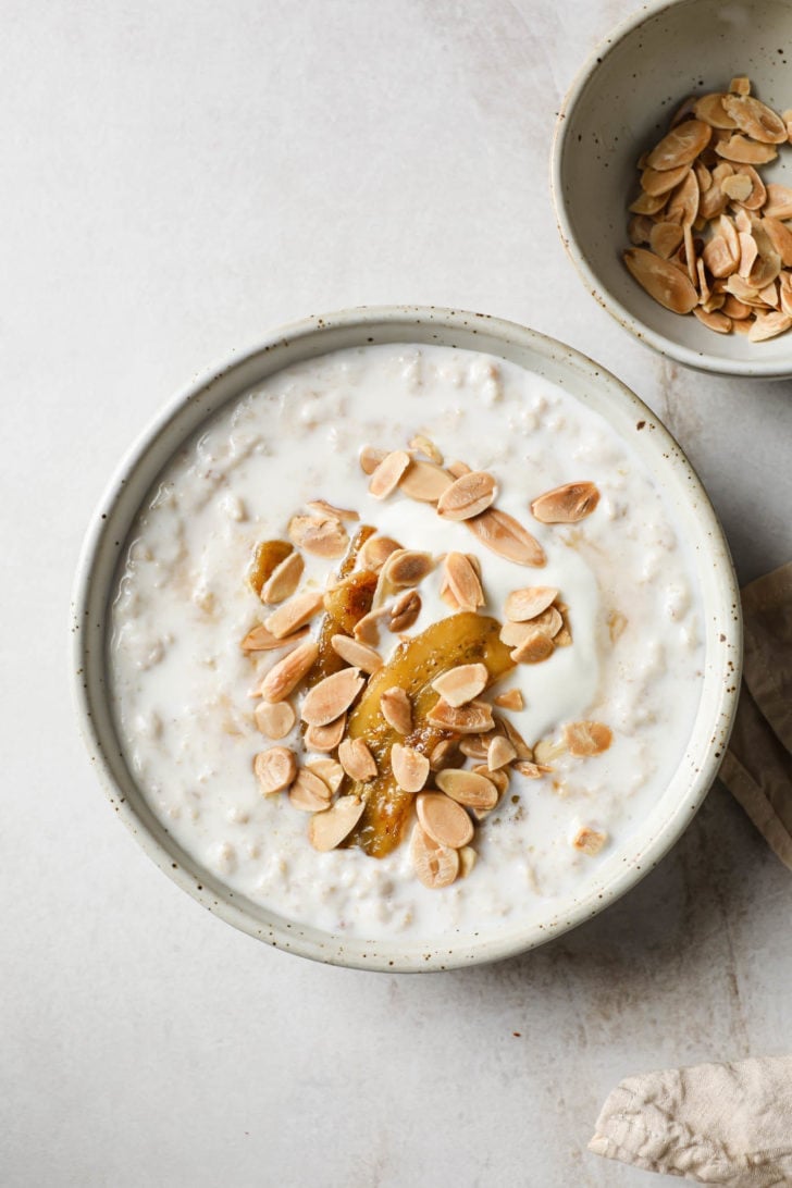 Oatmeal with milk in a bowl with almonds on the side.