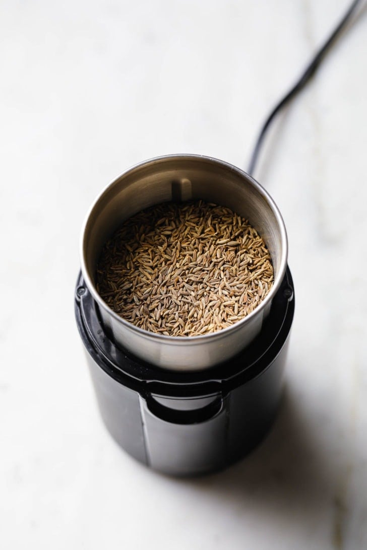 Cumin seeds in a spice grinder ready to be ground.