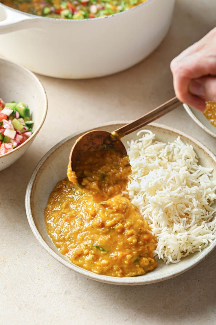 Scooping Masoor dal onto a bowl with rice.