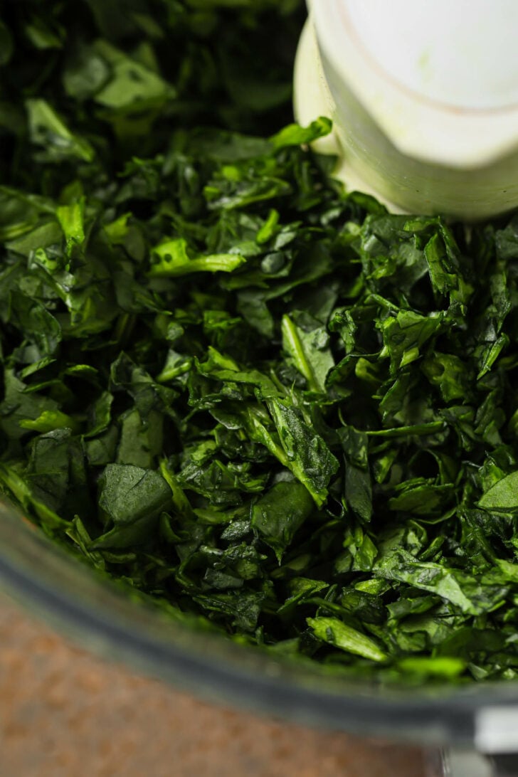 Close up of chopped spinach in a food processor.