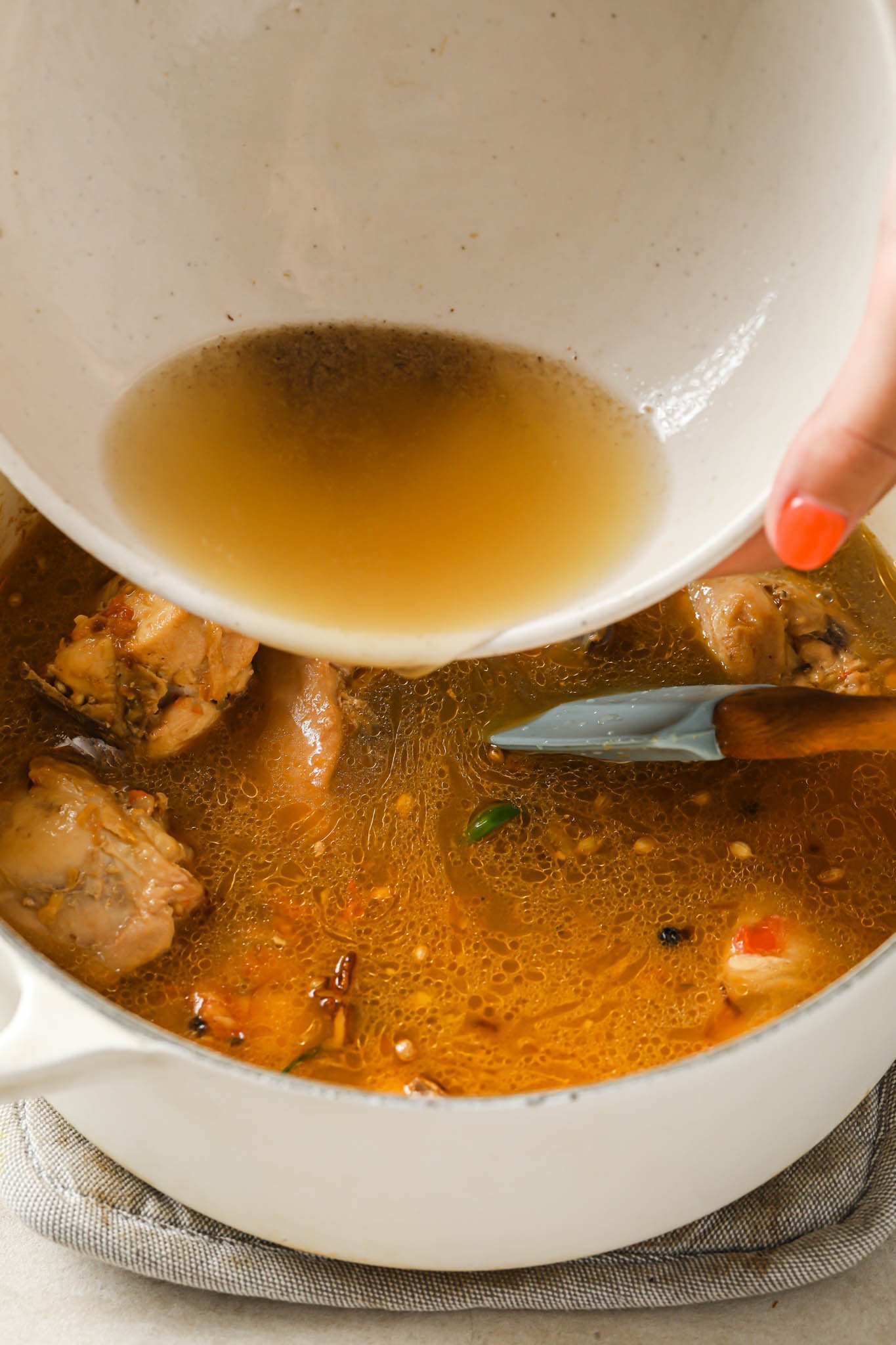 Adding broth to cooked chicken.