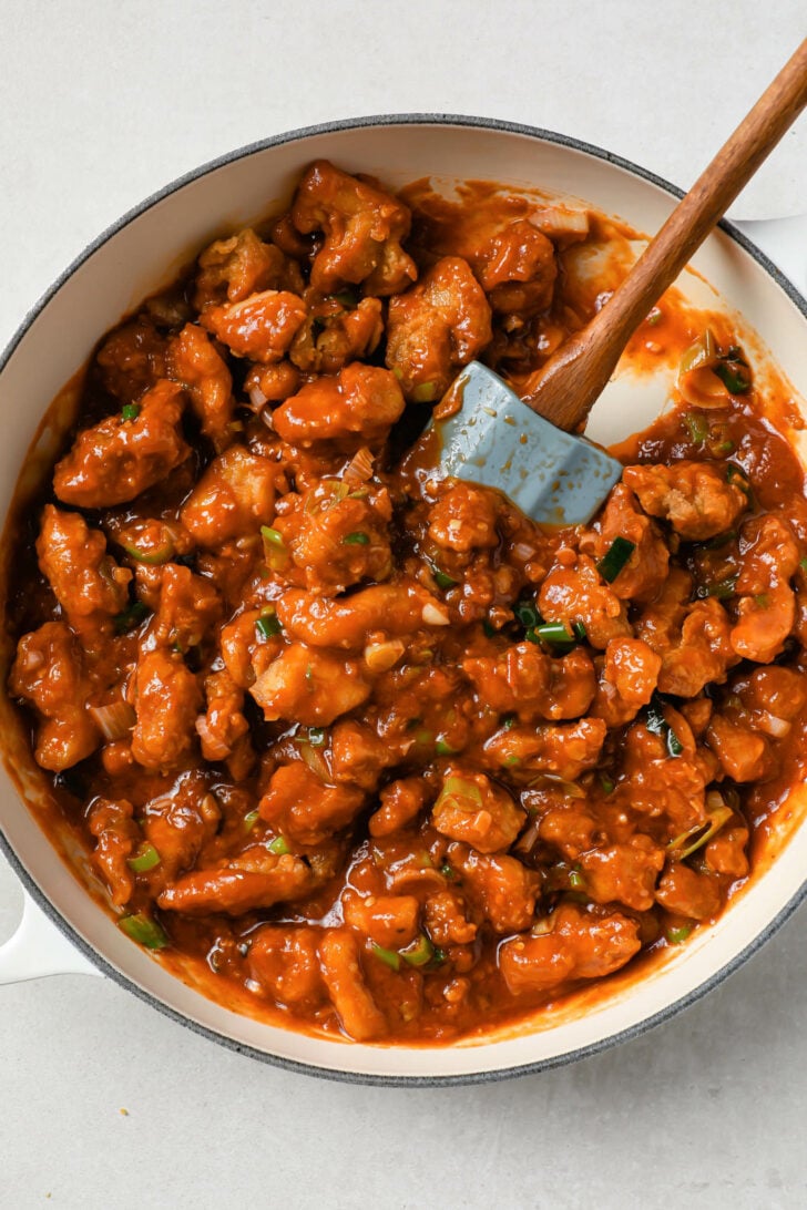 Manchurian chicken in a pot with a rubber spatula.