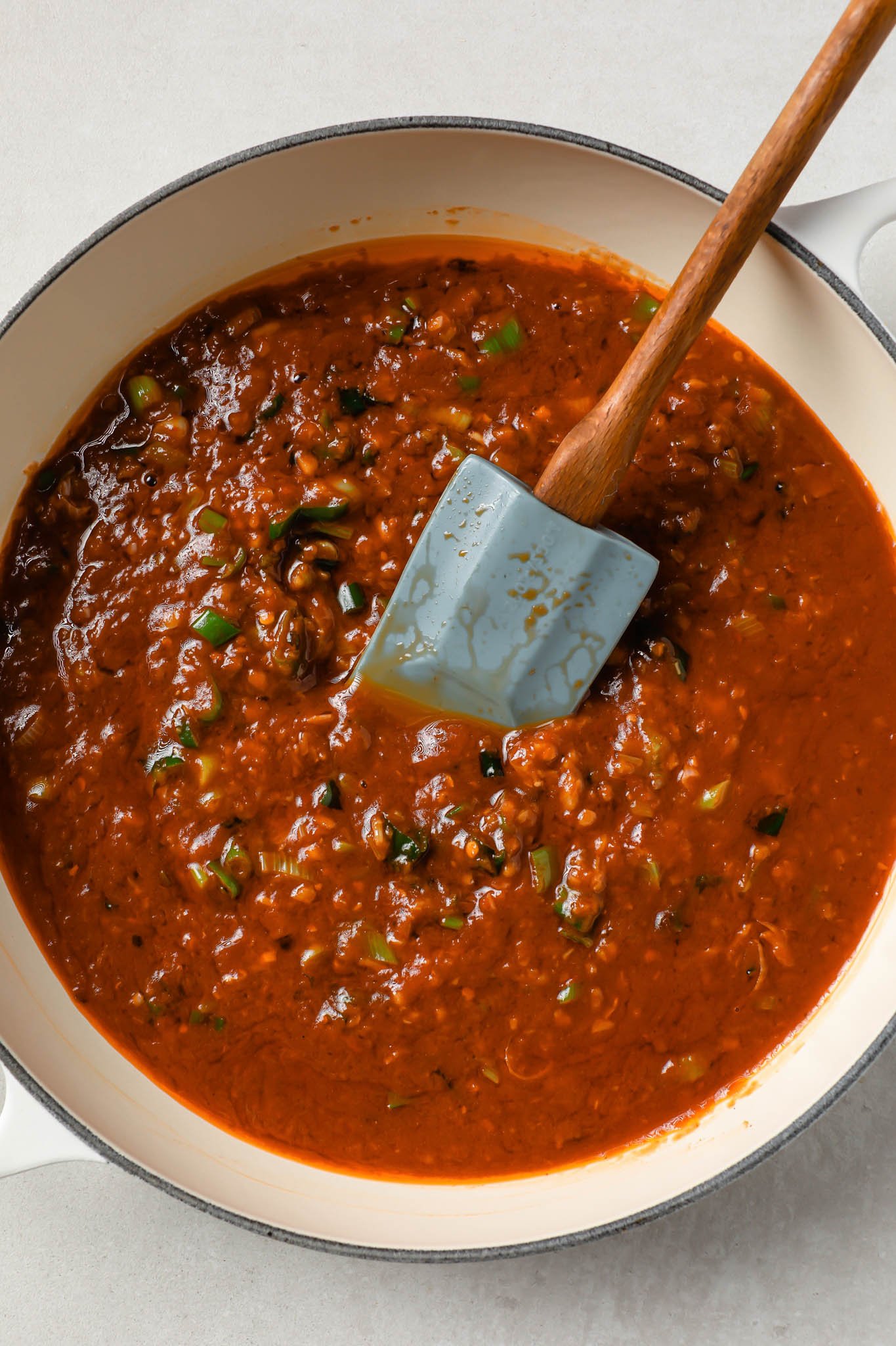 Manchurian sauce in a pot with a rubber spatula.
